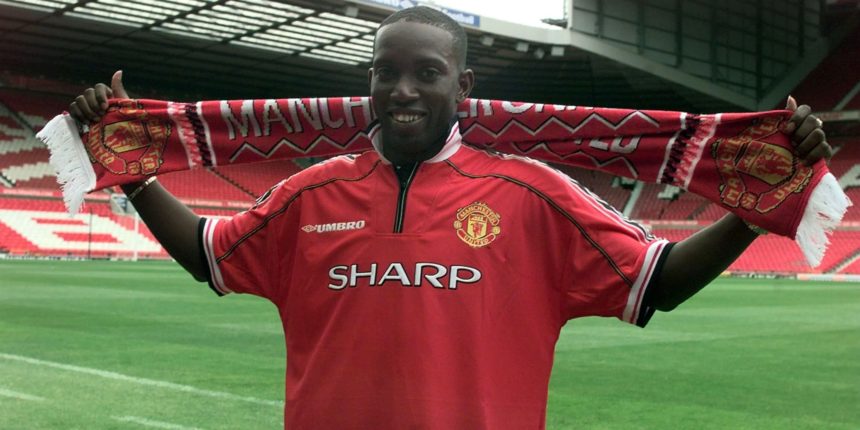 Dwight Yorke cầm chiếc khăn của Manchester United sau khi ký hợp đồng với câu lạc bộ.