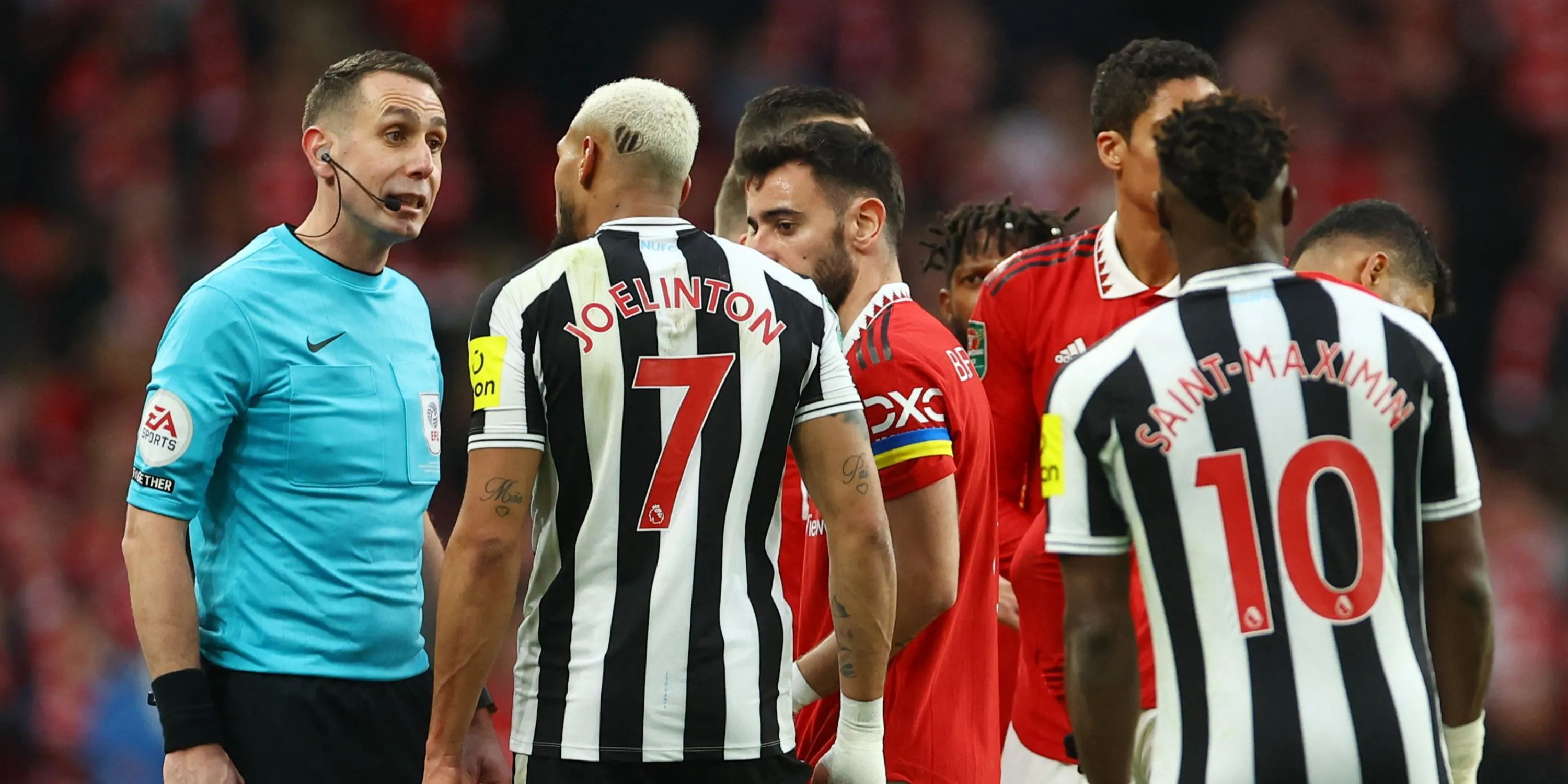Trọng tài David Coote đang trao đổi với các cầu thủ Newcastle trên sân.